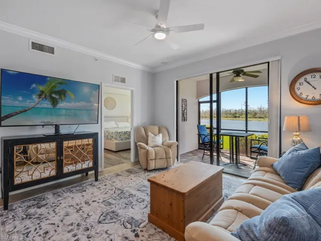 Living room featuring visible vents, crown molding, ceiling fan, and a water view