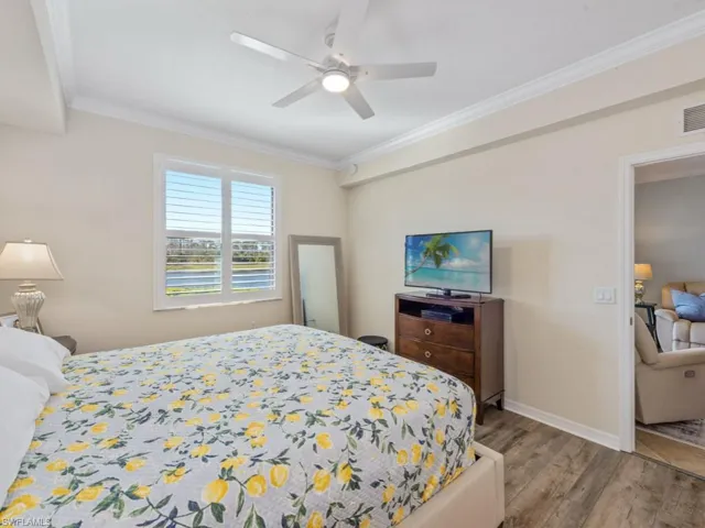 Bedroom featuring wood finished floors, visible vents, baseboards, ceiling fan, and crown molding