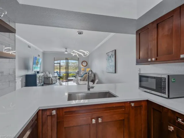 Kitchen featuring a sink, stainless steel microwave, open floor plan, a peninsula, and light countertops