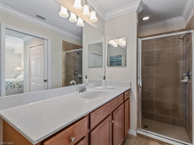 Ensuite bathroom featuring connected bathroom, a stall shower, and crown molding