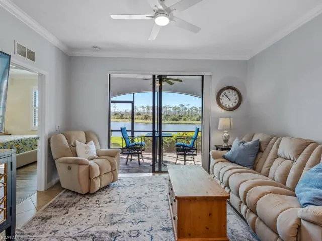Living room with light tile patterned floors, a ceiling fan, visible vents, a water view, and crown molding