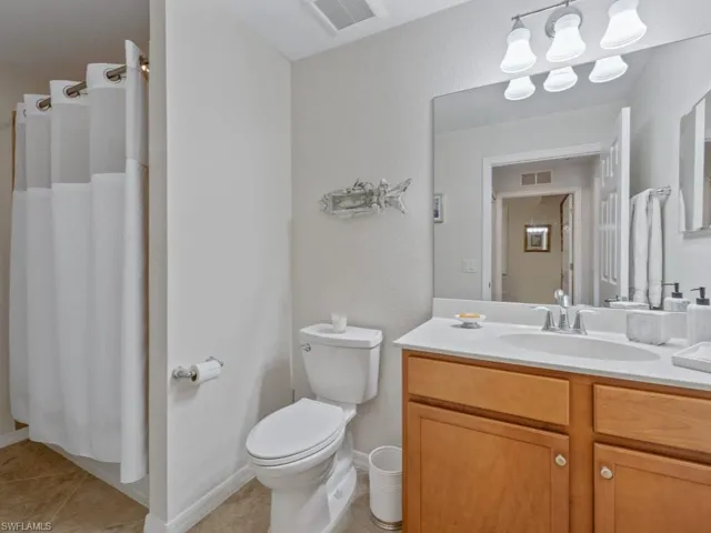 Bathroom featuring tile patterned floors, visible vents, toilet, and vanity
