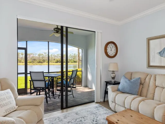 Tiled living room featuring a water view, baseboards, ornamental molding, and ceiling fan