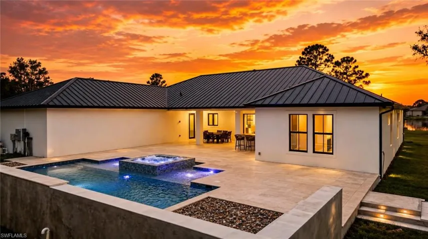 Modern residence showcasing a resort-style backyard with illuminated saltwater pool, integrated spa, and expansive patio