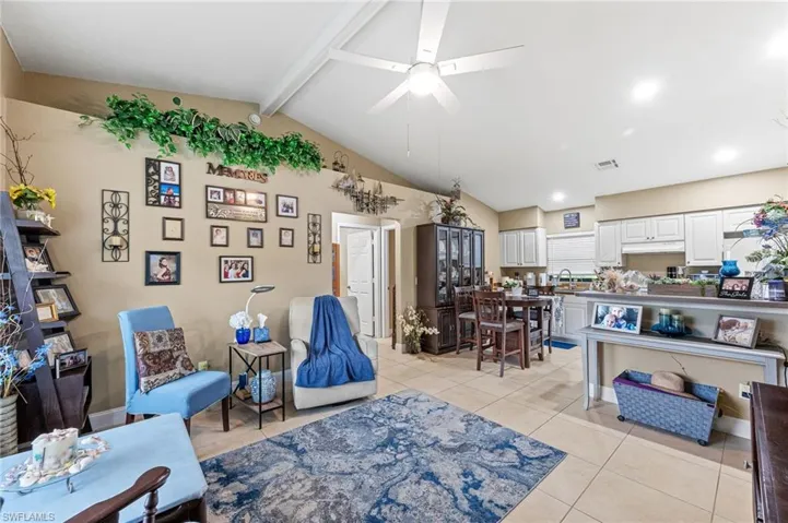 Living room with light tile patterned flooring, vaulted ceiling with beams, sink, and ceiling fan