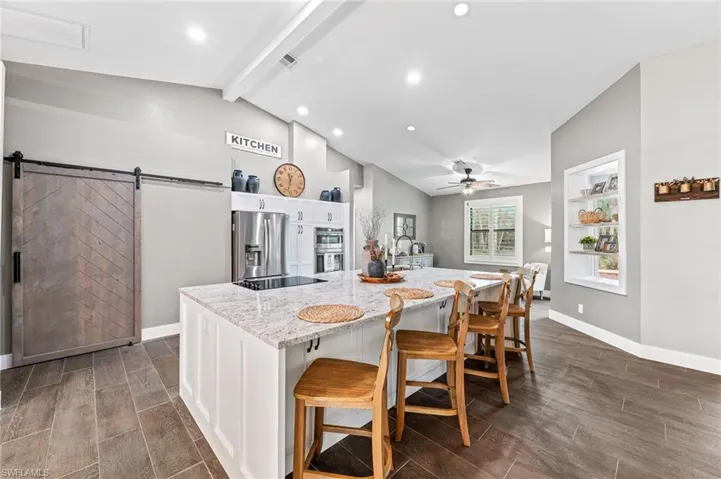 Kitchen featuring white cabinetry, stainless steel appliances, a kitchen breakfast bar, and a large island with sink