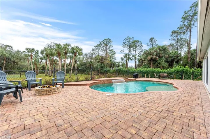 View of pool with pool water feature, a patio, and a fire pit