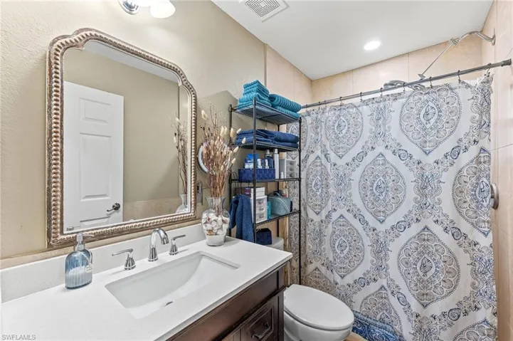 Bathroom with a shower with curtain, vanity, and toilet
