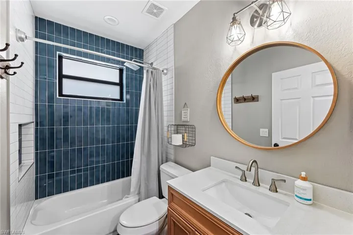 Full bathroom with shower / bathtub combination with curtain, vanity, and toilet