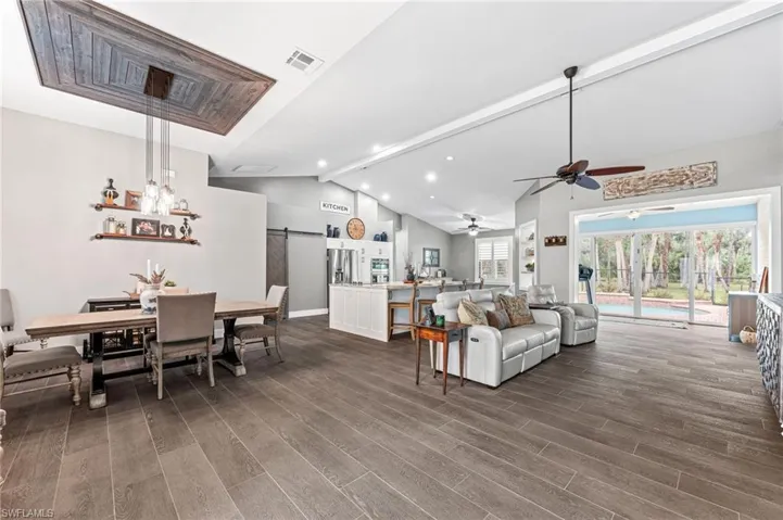 Living room with lofted ceiling with beams and a barn door