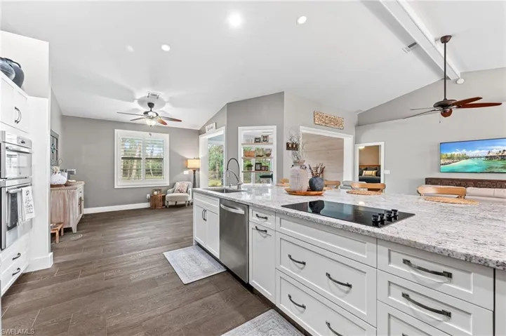 Kitchen featuring sink, appliances with stainless steel finishes, white cabinetry, light stone countertops, and dark hardwood / wood-style flooring