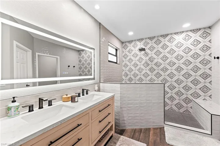 Bathroom featuring vanity, a tile shower, and tile walls