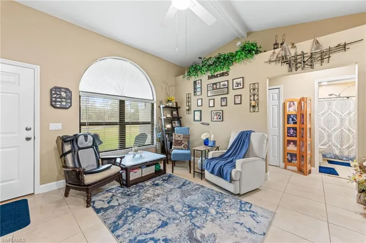 Sitting room with ceiling fan, lofted ceiling with beams, and light tile patterned floors