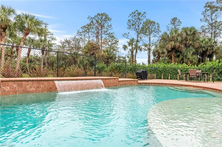 View of swimming pool featuring pool water feature and a grill