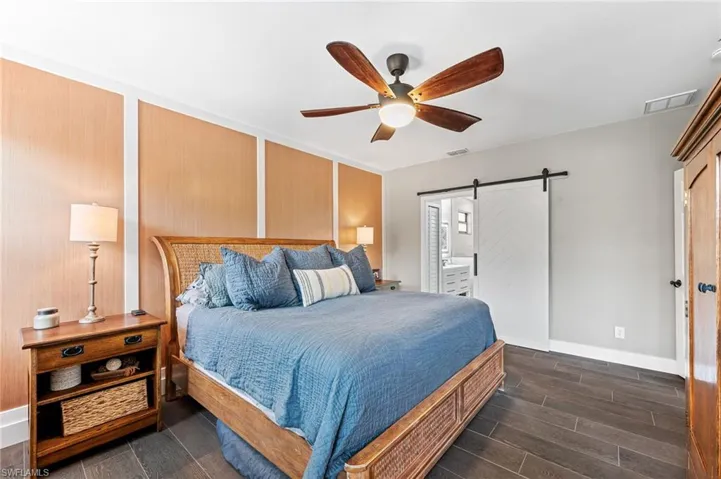 Bedroom featuring ceiling fan, connected bathroom, and a barn door