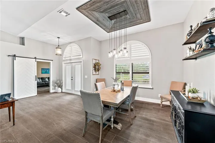 Dining room with a barn door and dark wood-type flooring