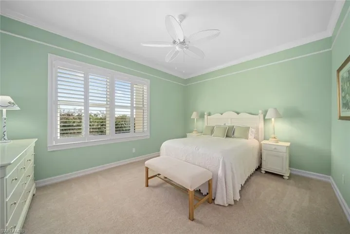 Bedroom with light carpet, ceiling fan, and crown molding