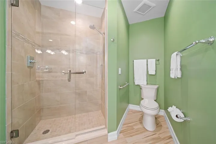 Bathroom featuring hardwood / wood-style flooring, toilet, and a shower with shower door
