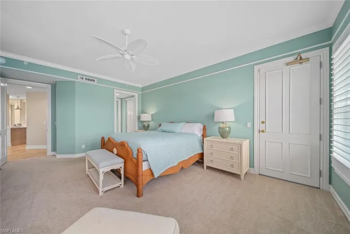 Carpeted bedroom with ceiling fan and ornamental molding