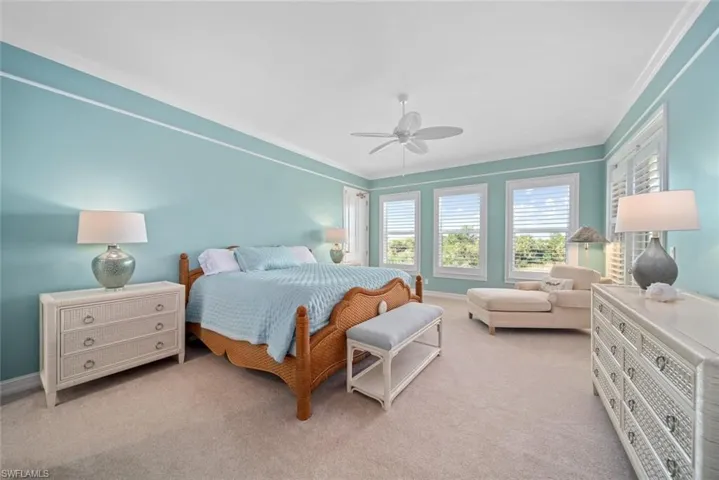 Carpeted bedroom featuring ceiling fan and crown molding