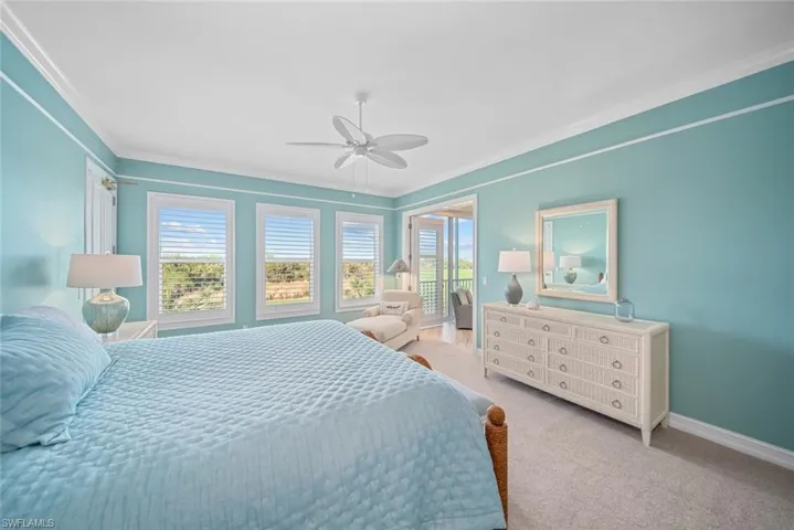 Carpeted bedroom with ceiling fan and ornamental molding