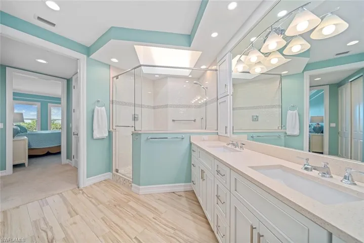 Bathroom with a shower with shower door, wood-type flooring, vanity, and a skylight