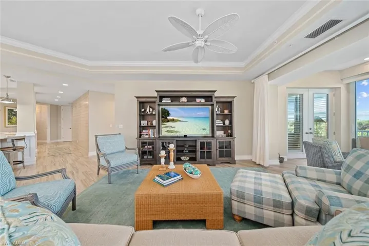 Living room featuring french doors, light wood-type flooring, ceiling fan, and ornamental molding
