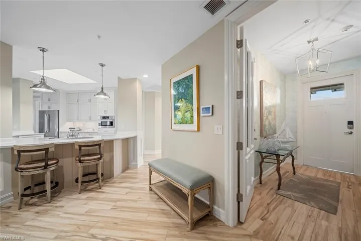 Kitchen with white cabinetry, light hardwood / wood-style floors, decorative light fixtures, a kitchen bar, and appliances with stainless steel finishes