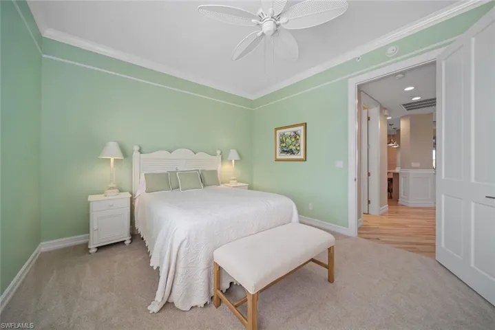 Bedroom with ceiling fan, light colored carpet, and ornamental molding