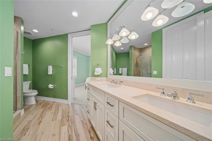 Bathroom with toilet, vanity, an enclosed shower, and hardwood / wood-style flooring