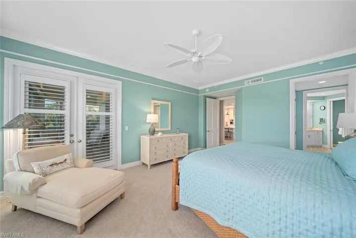 Carpeted bedroom featuring ceiling fan, access to exterior, crown molding, and ensuite bath