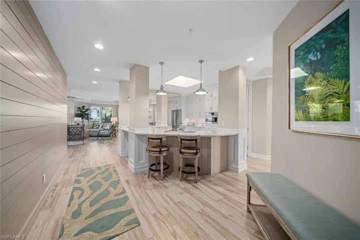 Kitchen with a breakfast bar, pendant lighting, light wood-type flooring, and white cabinetry
