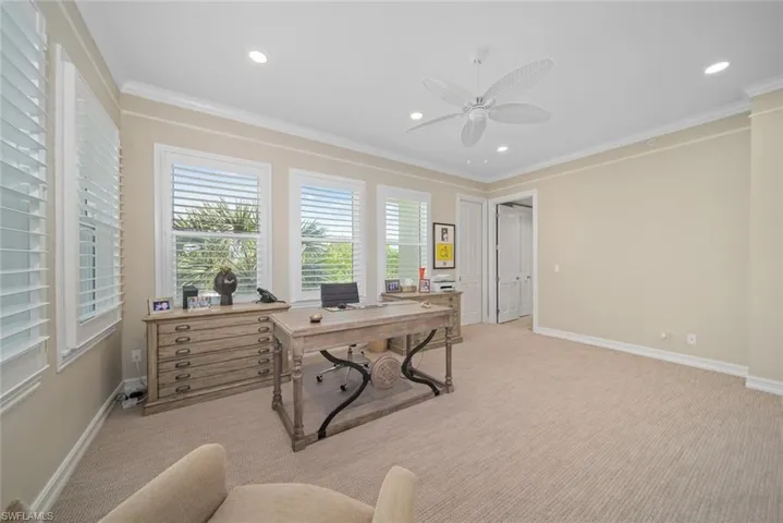 Carpeted office featuring ceiling fan and crown molding