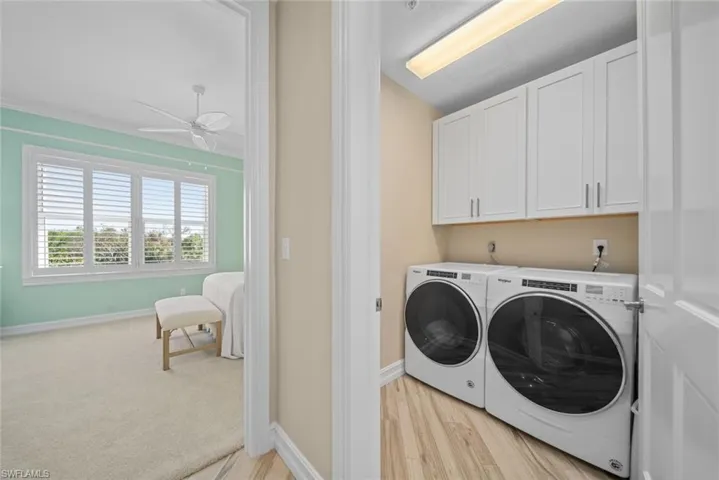 Laundry area featuring washing machine and dryer, ceiling fan, cabinets, and light wood-type flooring