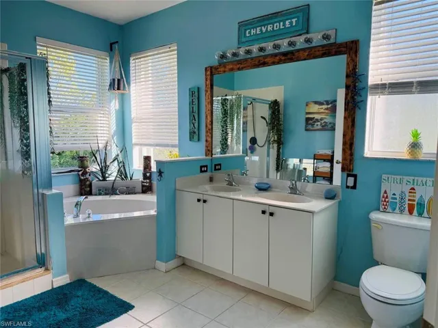 Full bathroom featuring a shower stall, a garden tub, double vanity, and light tile patterned floors