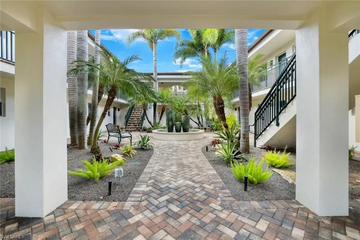 Covered walkway through tropical landscaping leading to the unit.
