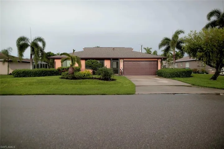 Ranch-style house featuring a garage and a front lawn