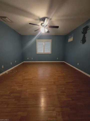 Empty room featuring ceiling fan and dark hardwood / wood-style flooring