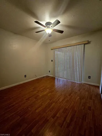 Unfurnished room featuring ceiling fan and dark wood-type flooring