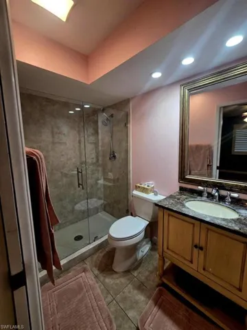 Bathroom featuring a shower with shower door, tile patterned floors, toilet, and vanity