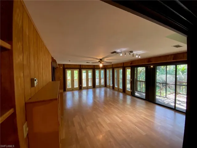 Unfurnished room featuring plenty of natural light, light hardwood / wood-style floors, and wooden walls