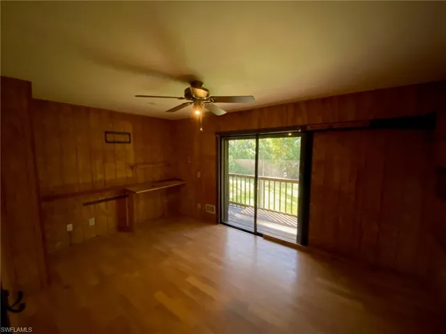 Unfurnished room with ceiling fan, wooden walls, and light hardwood / wood-style floors