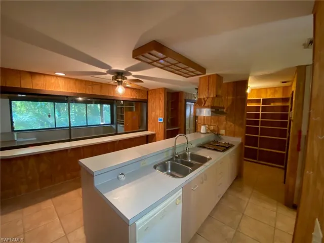 Kitchen with a center island, stainless steel gas stovetop, sink, white dishwasher, and light tile patterned floors