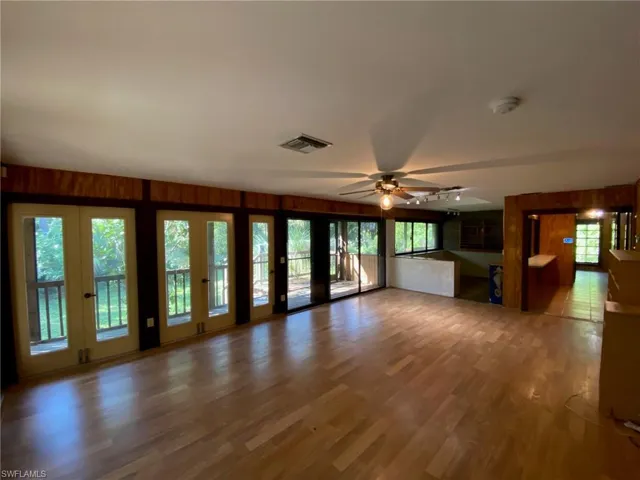Unfurnished living room featuring wood walls, hardwood / wood-style floors, and a wealth of natural light