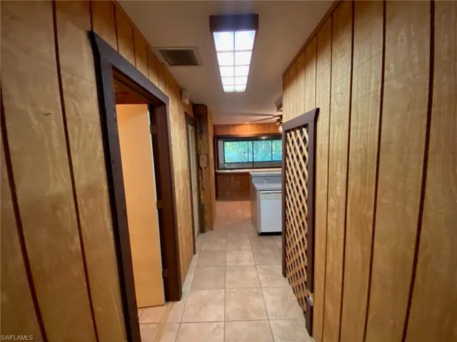 Corridor featuring light tile patterned floors and wooden walls