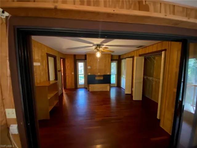 Unfurnished living room featuring ceiling fan and dark hardwood / wood-style floors