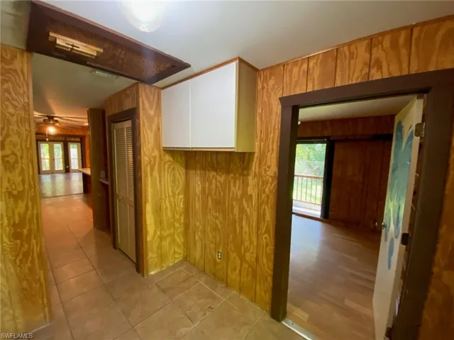Hall featuring light wood-type flooring and wood walls