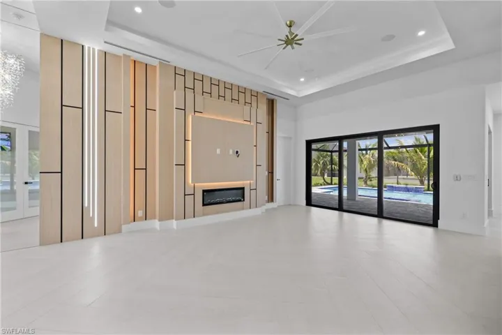 Unfurnished living room featuring a tray ceiling, a glass covered fireplace, a chandelier, recessed lighting, and a towering ceiling