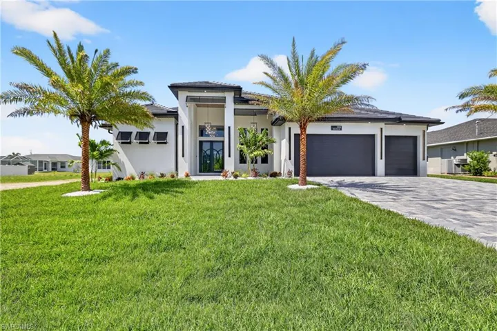Prairie-style home featuring an attached garage, concrete driveway, a front lawn, stucco siding, and a tiled roof
