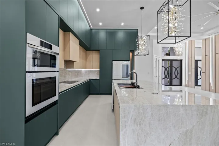 Kitchen with green cabinetry, a spacious island, double oven, refrigerator, and modern cabinets